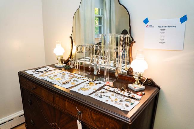 Vintage wooden dresser with a mirror displaying various women's jewelry, including necklaces, bracelets, and rings.